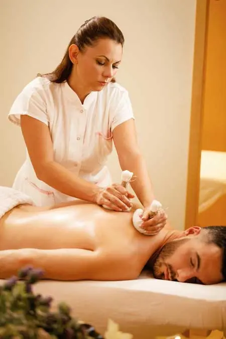female therapists massaging back man with thai herbal compress health spa